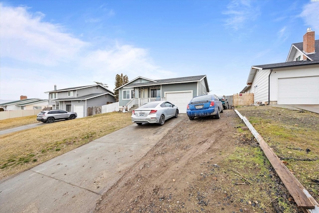 view of front of home with a garage, dirt driveway, fence, and a residential view