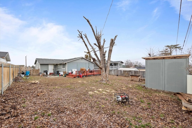 rear view of property with an outbuilding, a fenced backyard, a deck, and a storage unit