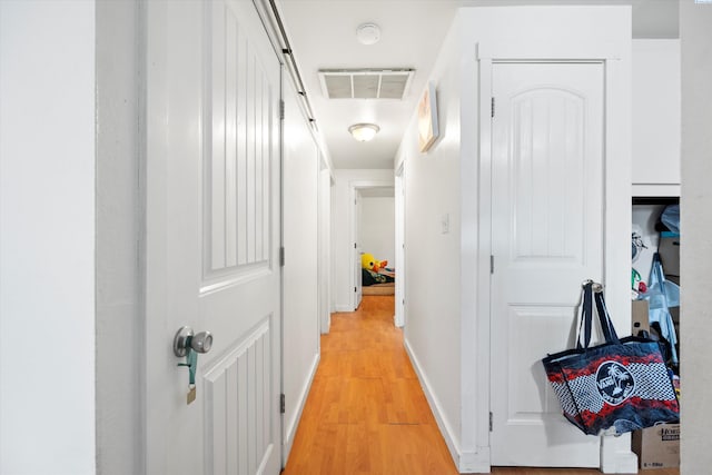 corridor featuring visible vents, light wood-style flooring, and baseboards