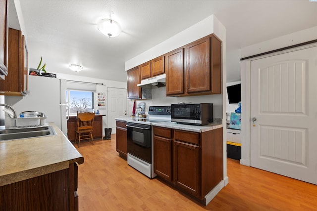 kitchen featuring white electric stove, light countertops, stainless steel microwave, a sink, and under cabinet range hood