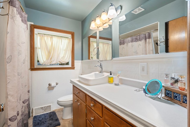 bathroom featuring tile patterned floors, vanity, toilet, and tile walls