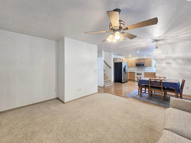 2650 Dornoch Pl, Richland, WA 99354 - living room with baseboards, stairs, light colored carpet, and a ceiling fan