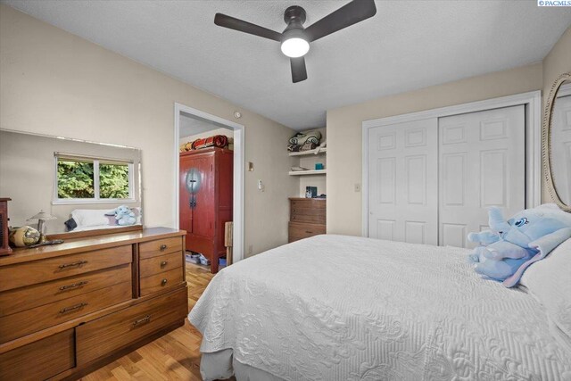 bedroom with a closet, a textured ceiling, a ceiling fan, and light wood-type flooring