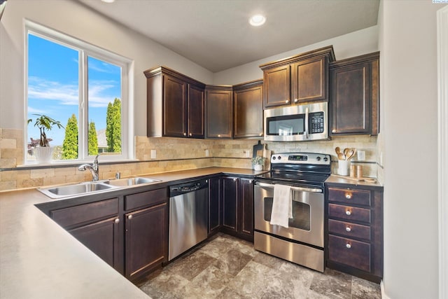 kitchen with appliances with stainless steel finishes, a sink, backsplash, dark brown cabinets, and recessed lighting