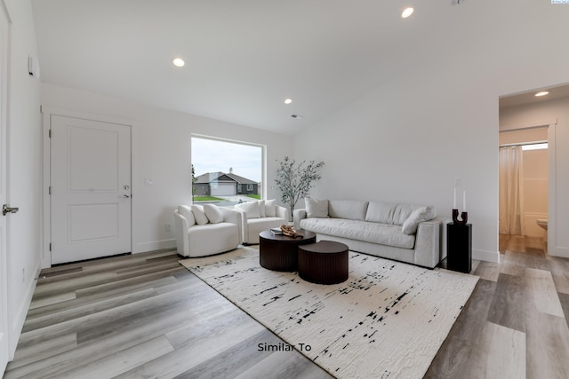 living room featuring vaulted ceiling and light wood-type flooring