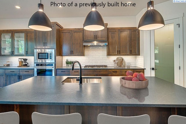 kitchen featuring pendant lighting, sink, a breakfast bar area, appliances with stainless steel finishes, and backsplash