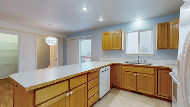 kitchen featuring decorative light fixtures, sink, a notable chandelier, kitchen peninsula, and white appliances