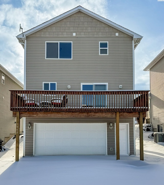 snow covered property featuring a garage and a deck