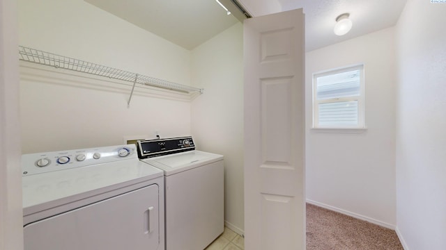 clothes washing area featuring light carpet and washer and clothes dryer