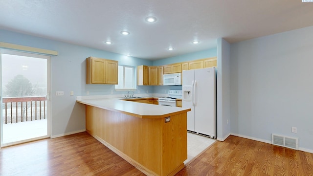 kitchen with white appliances, kitchen peninsula, light hardwood / wood-style floors, and light brown cabinets