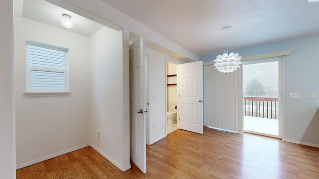 unfurnished dining area featuring an inviting chandelier and light hardwood / wood-style floors