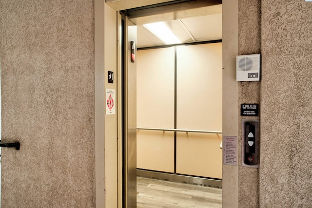 details with hardwood / wood-style flooring and elevator