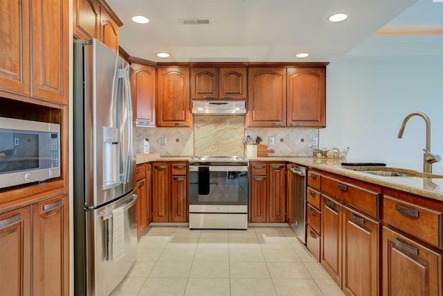 kitchen with tasteful backsplash, sink, light tile patterned floors, stainless steel appliances, and light stone countertops