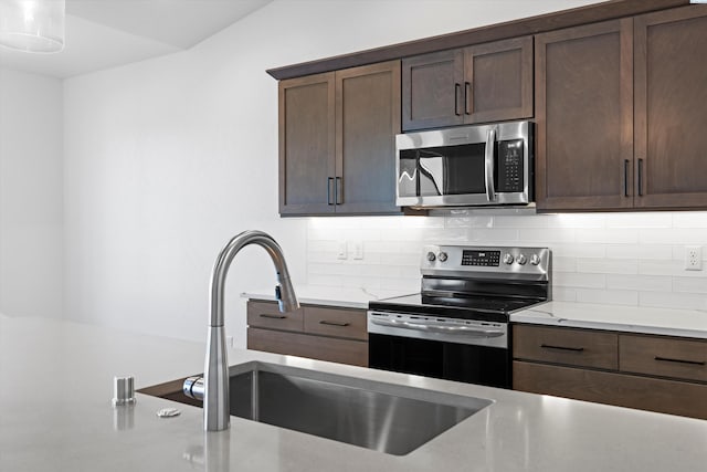 6701 Sockeye Ln, Pasco, WA 99301 - kitchen featuring appliances with stainless steel finishes, sink, backsplash, dark brown cabinetry, and light stone countertops