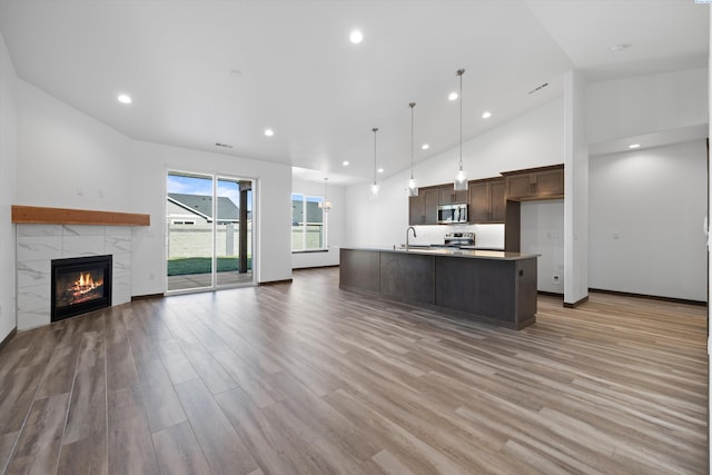 6701 Sockeye Ln, Pasco, WA 99301 - kitchen featuring a tile fireplace, decorative light fixtures, a kitchen island with sink, stainless steel appliances, and dark brown cabinets