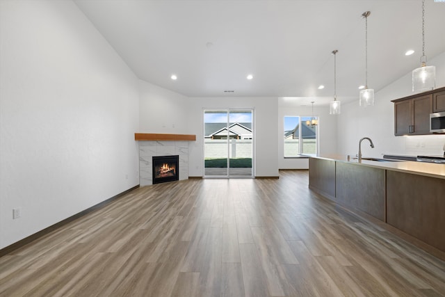 6701 Sockeye Ln, Pasco, WA 99301 - kitchen featuring decorative light fixtures, sink, a tiled fireplace, dark brown cabinets, and light hardwood / wood-style flooring