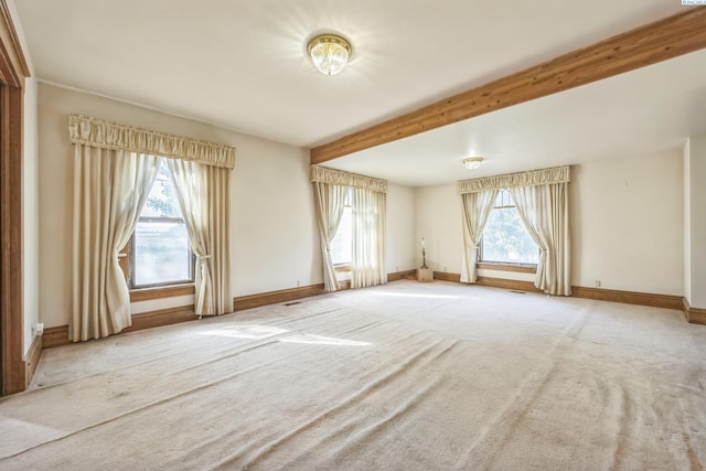 carpeted empty room with beam ceiling