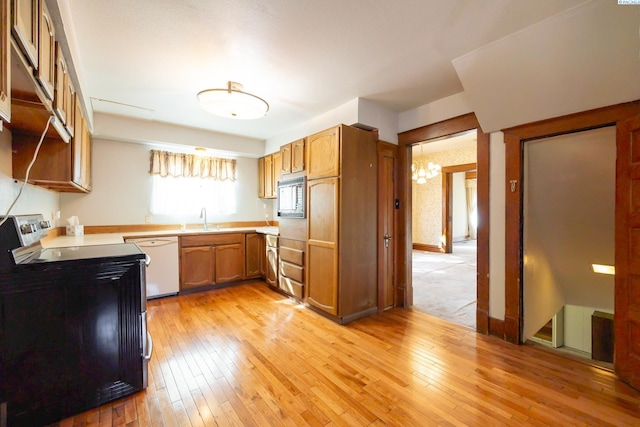 kitchen with sink, stainless steel appliances, light hardwood / wood-style floors, and a chandelier