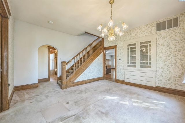 carpeted empty room with a notable chandelier