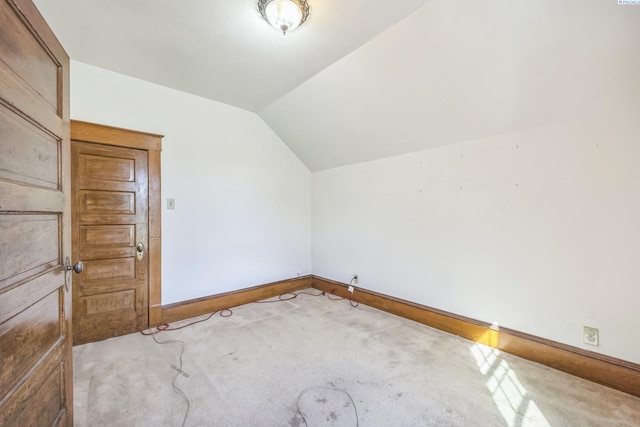 bonus room with vaulted ceiling and light carpet