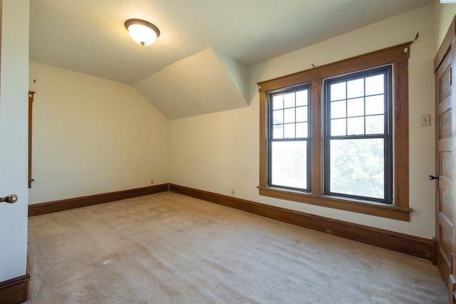 bonus room with lofted ceiling and light colored carpet