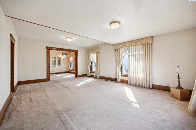 carpeted spare room featuring an inviting chandelier