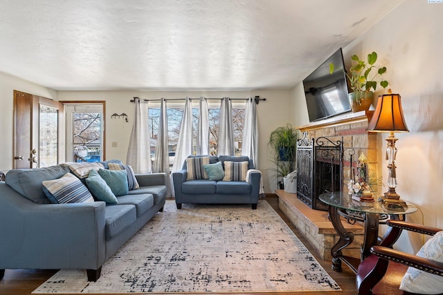 living area featuring a textured ceiling, plenty of natural light, a fireplace, and wood finished floors