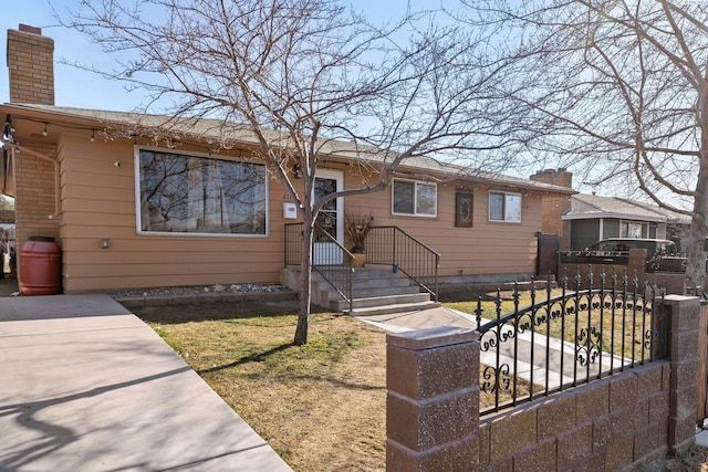 single story home with a chimney and a fenced front yard