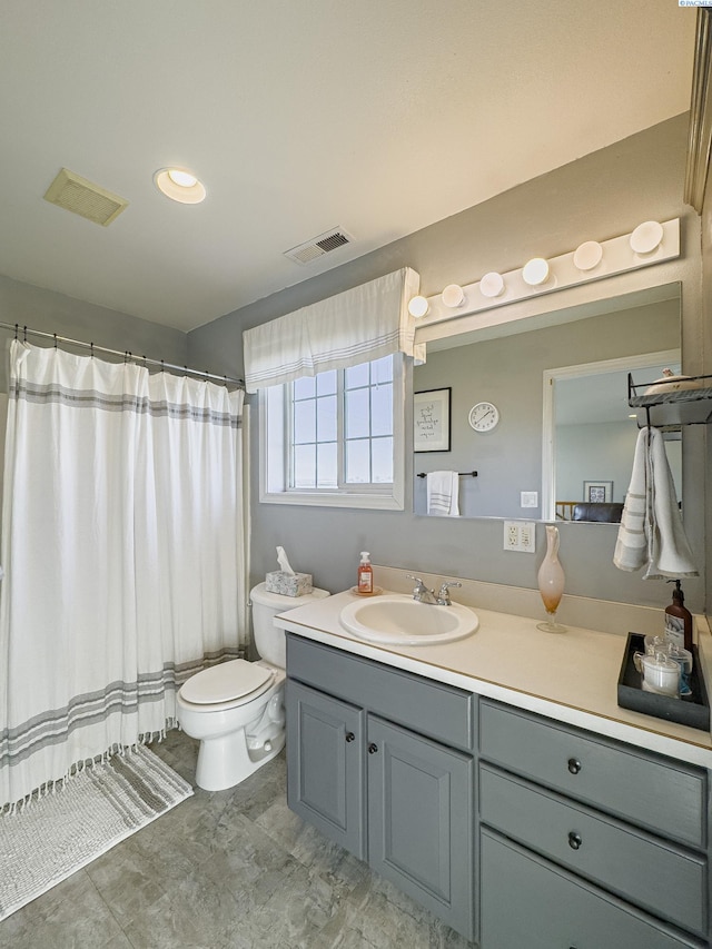 bathroom featuring vanity, walk in shower, and toilet