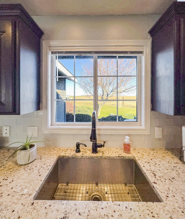 room details with sink, decorative backsplash, dark brown cabinets, and light stone countertops