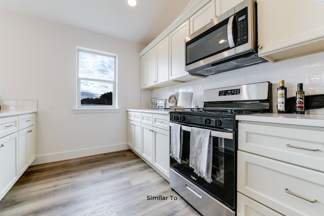 2880 S Osborne St, Kennewick, WA 99338 - kitchen with light wood-style flooring, white cabinets, appliances with stainless steel finishes, light countertops, and decorative backsplash