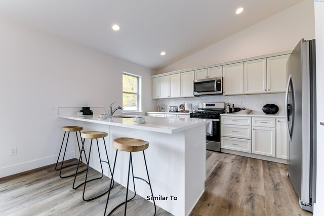 2880 S Osborne St, Kennewick, WA 99338 - kitchen with a peninsula, a breakfast bar, appliances with stainless steel finishes, lofted ceiling, and backsplash