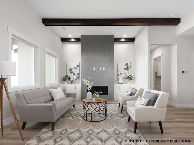 living room featuring beamed ceiling, a premium fireplace, and light wood-type flooring