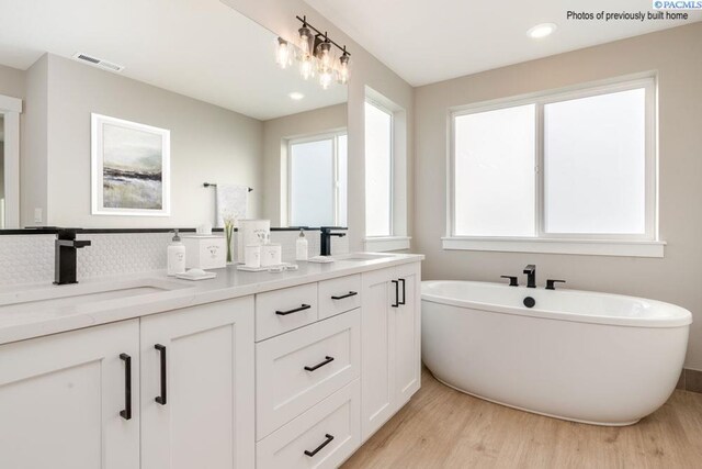 2816 Avrio Ave, Richland, WA 99354 - bathroom with wood finished floors, double vanity, a freestanding tub, tasteful backsplash, and recessed lighting