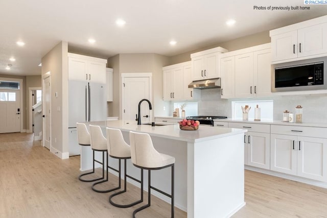 2816 Avrio Ave, Richland, WA 99354 - kitchen featuring built in microwave, under cabinet range hood, a sink, freestanding refrigerator, and light wood-style floors