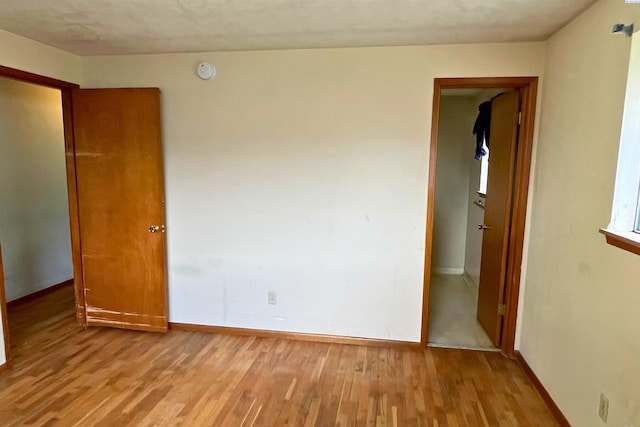 spare room with wood finished floors, a smoke detector, and baseboards