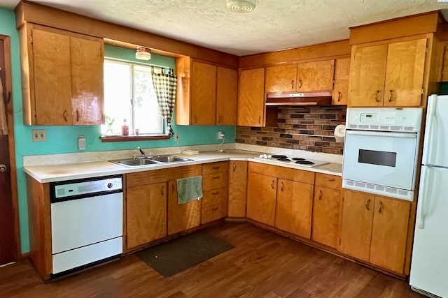 kitchen featuring white appliances, under cabinet range hood, a sink, dark wood finished floors, and light countertops