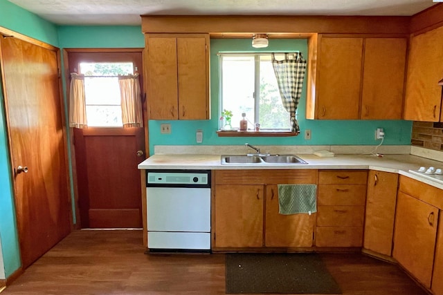 kitchen with a sink, white appliances, light countertops, dark wood finished floors, and brown cabinetry