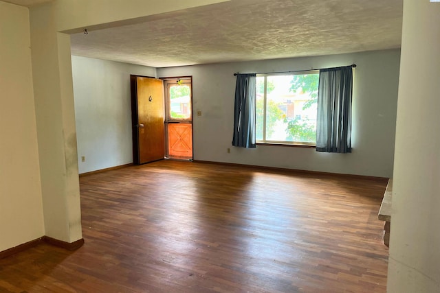 unfurnished room with wood finished floors, a textured ceiling, and baseboards