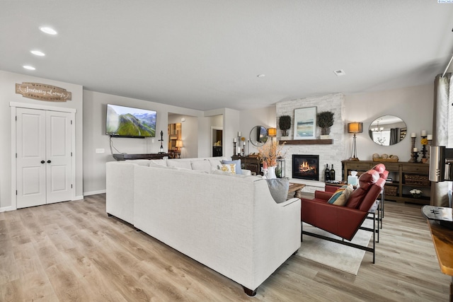 living room with a stone fireplace and light hardwood / wood-style floors