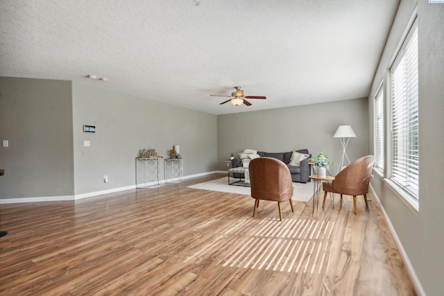sitting room featuring baseboards, wood finished floors, ceiling fan, and a textured ceiling