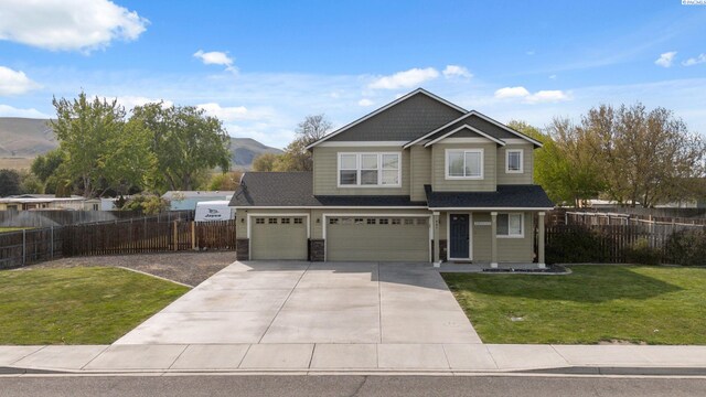 craftsman inspired home featuring a front lawn, a mountain view, driveway, an attached garage, and fence