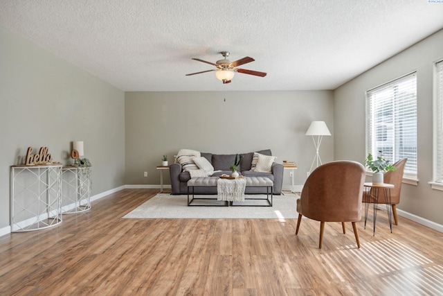 living area with a textured ceiling, wood finished floors, a ceiling fan, and baseboards