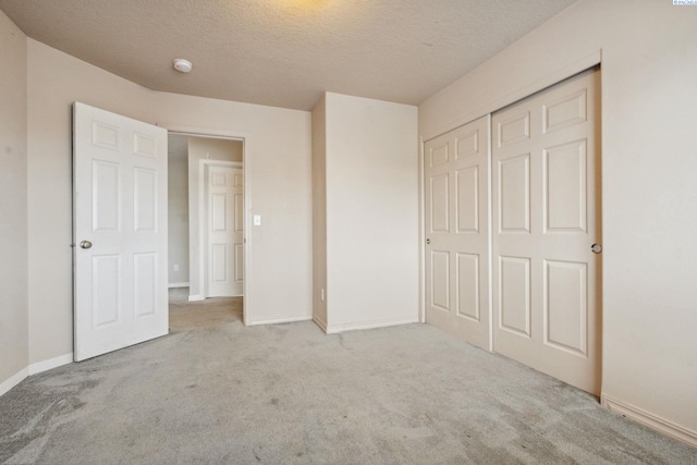 unfurnished bedroom with a textured ceiling, a closet, baseboards, and carpet floors