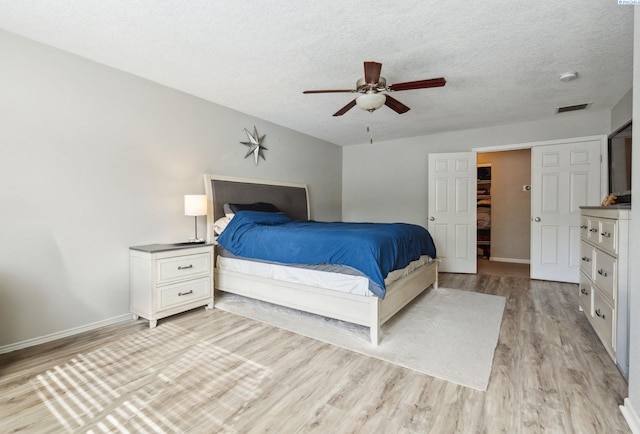 bedroom featuring a textured ceiling, light wood-type flooring, a ceiling fan, and baseboards