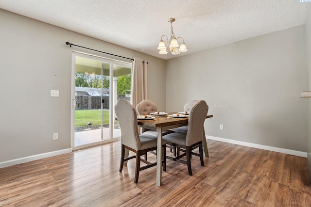 dining room with a textured ceiling, an inviting chandelier, wood finished floors, and baseboards