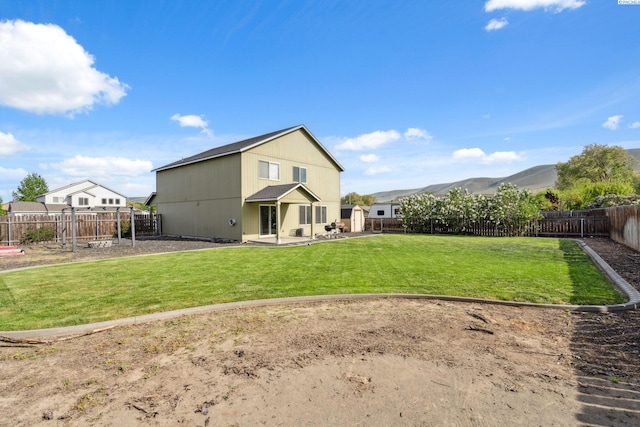 rear view of house with a patio, a yard, a fenced backyard, and a mountain view