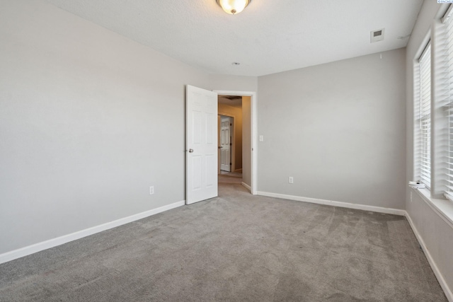 unfurnished bedroom with carpet, visible vents, multiple windows, and baseboards