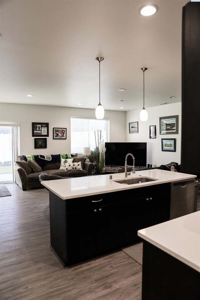 kitchen with plenty of natural light, dark hardwood / wood-style floors, hanging light fixtures, and a center island with sink