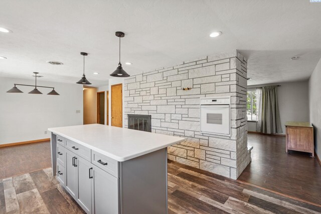 1815 W 16th Ave, Kennewick, WA 99337 - kitchen with white oven, a stone fireplace, dark wood-style floors, recessed lighting, and a kitchen island